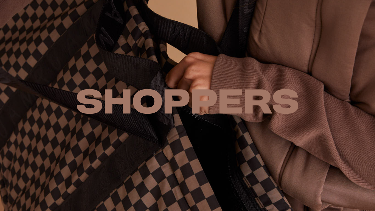 Close-up of hands reaching into checkered neoprene shopper bag. The word ‘Shopper’ is displayed in large text across the image.